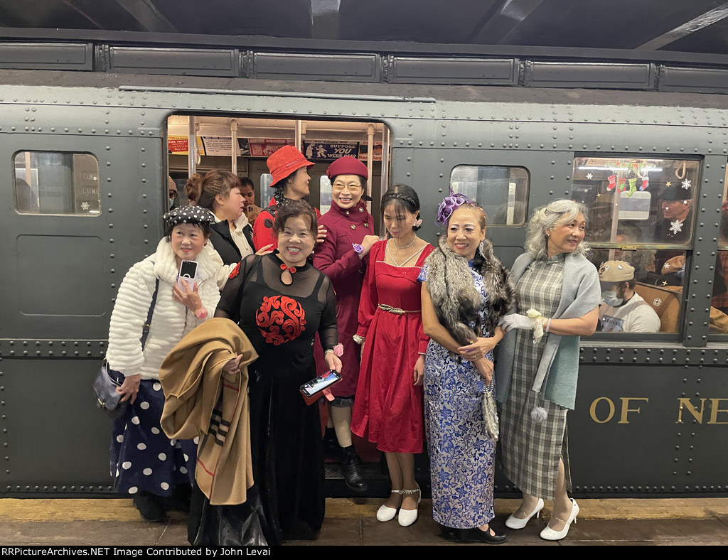 People dessed up in amazing costumes posing next to the NYCTA Holiday Train at 2nd Avenue Station on Manhattans Lower East Side